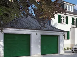 Doppelgarage mit zwei moosgrünen Sektionaltoren an einem weiß verputzten Haus