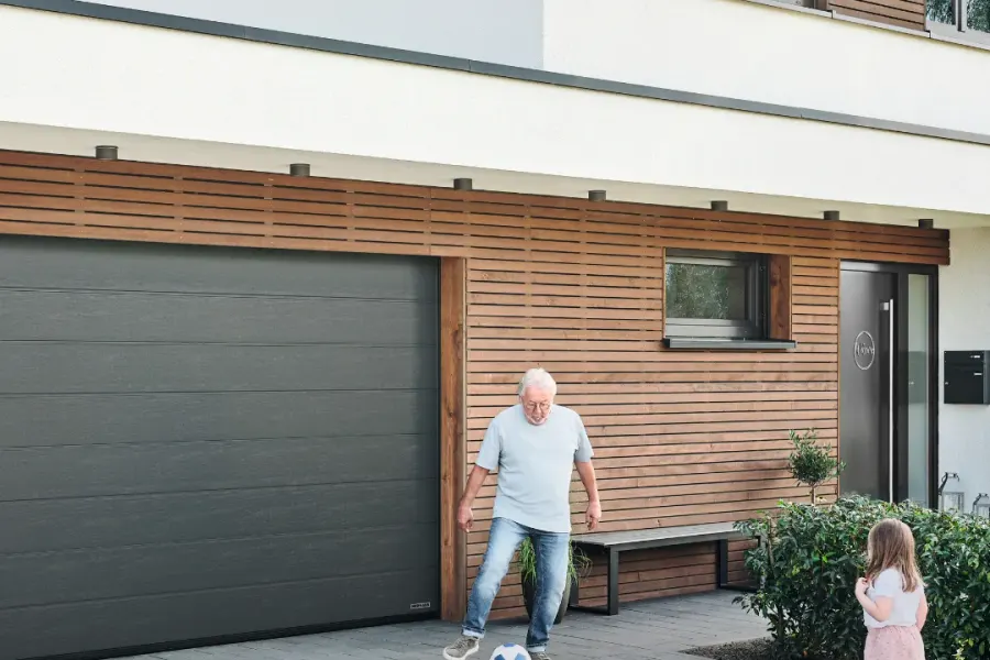 Vater und Tochter spielen Fußball vor der geöffneten Garage ihres Hauses