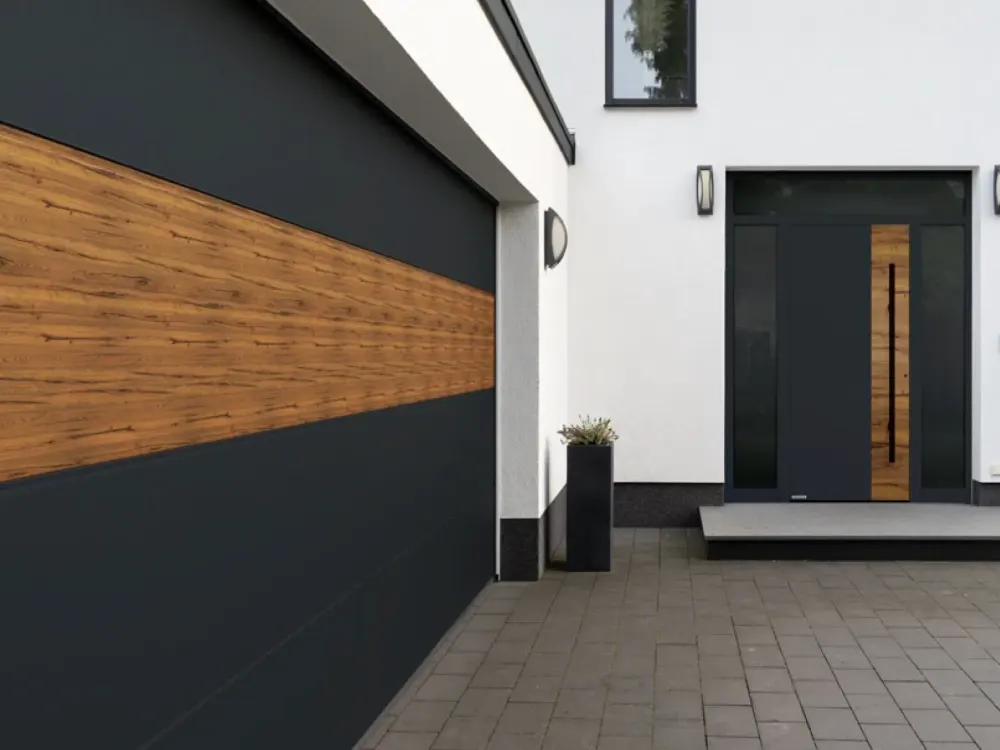 Hausfassade aus dunklem Putz und Holzlamellen mit bündig eingesetztem Garagentor
