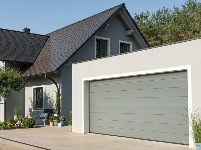 Modernes Haus mit hellgrauem Garagentor und gepflegtem Rasen