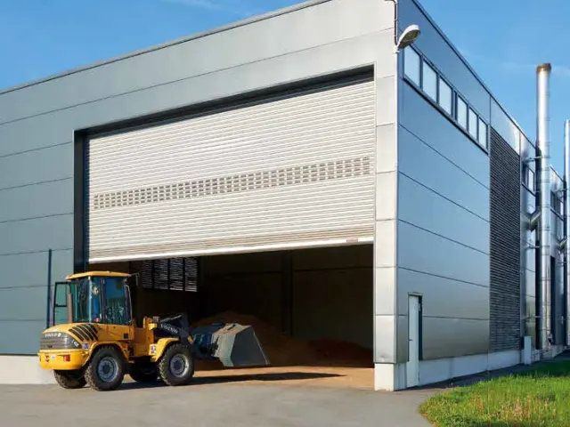 Radlader vor einer Industriehalle mit großem geöffnetem Tor
