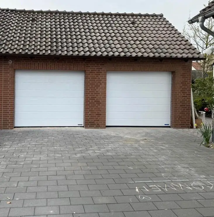 Dieselbe Klinkergarage mit zwei weißen Hörmann Sektionaltoren