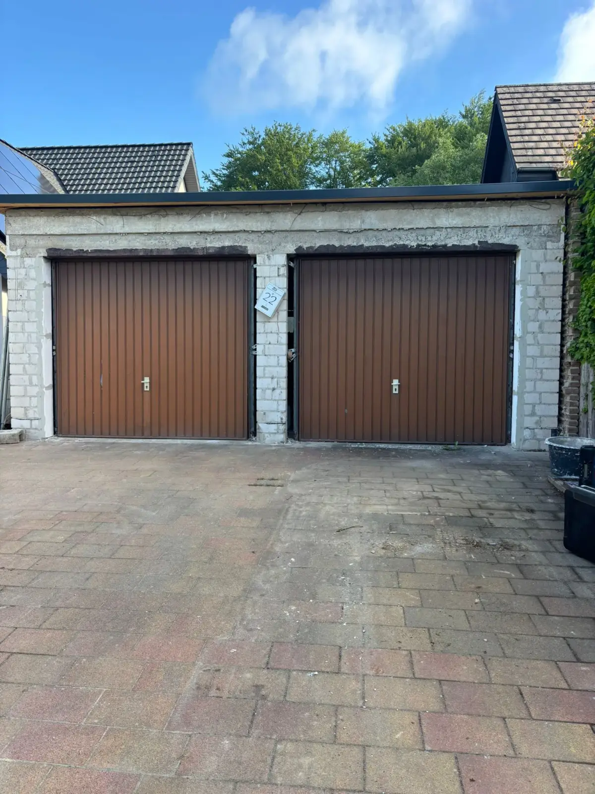 Doppelgarage mit zwei alten braunen Schwingtoren und schmalen Durchfahrten